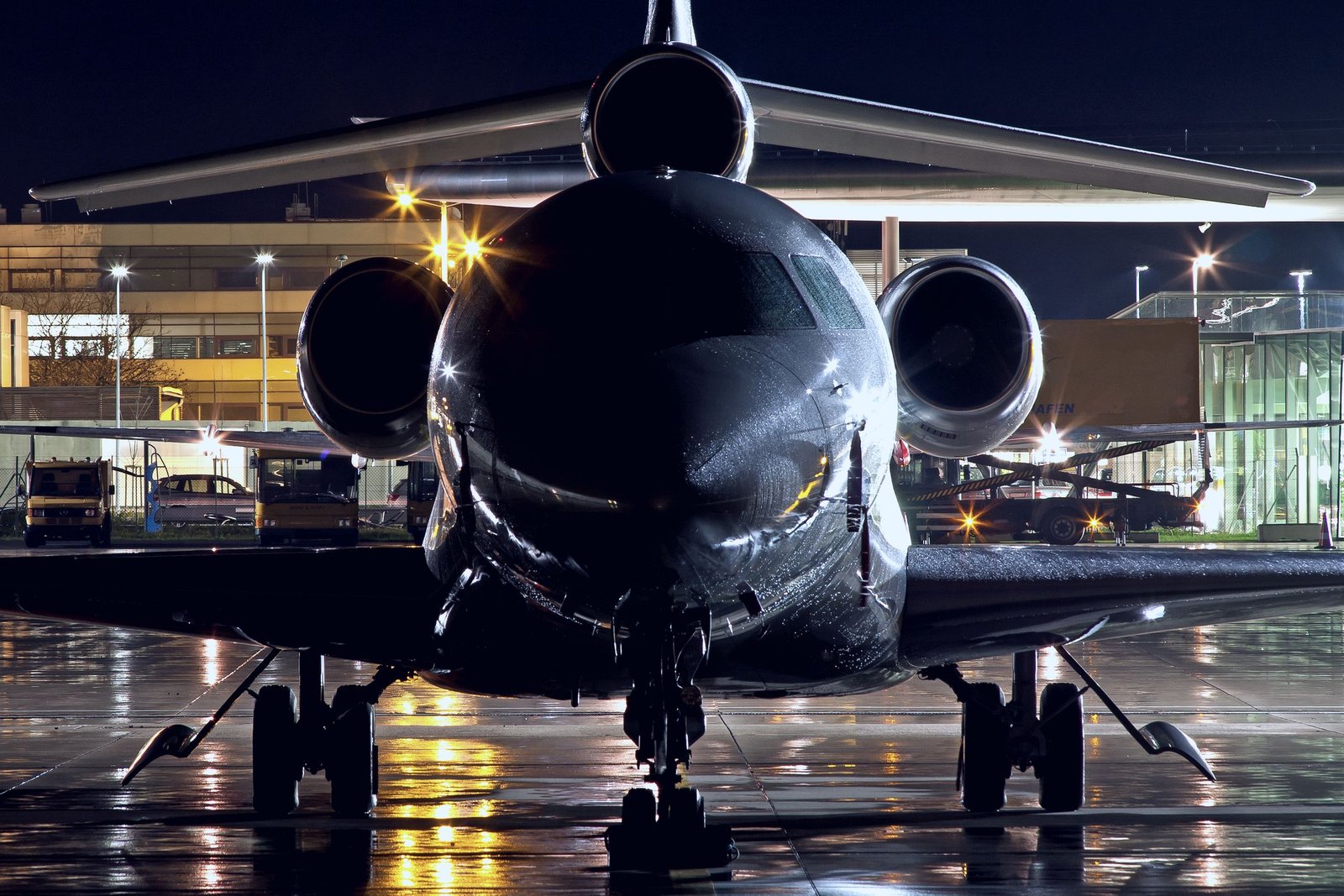 Business jet on the apron at night, hangar lights on the wet ramp