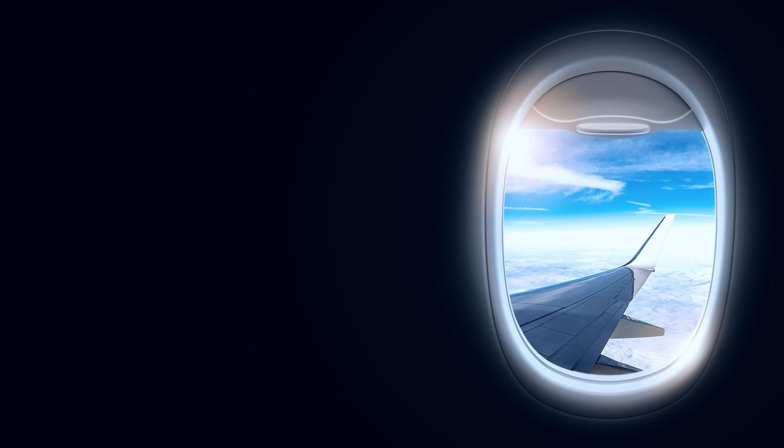View through a cabin window onto the wing above cloud